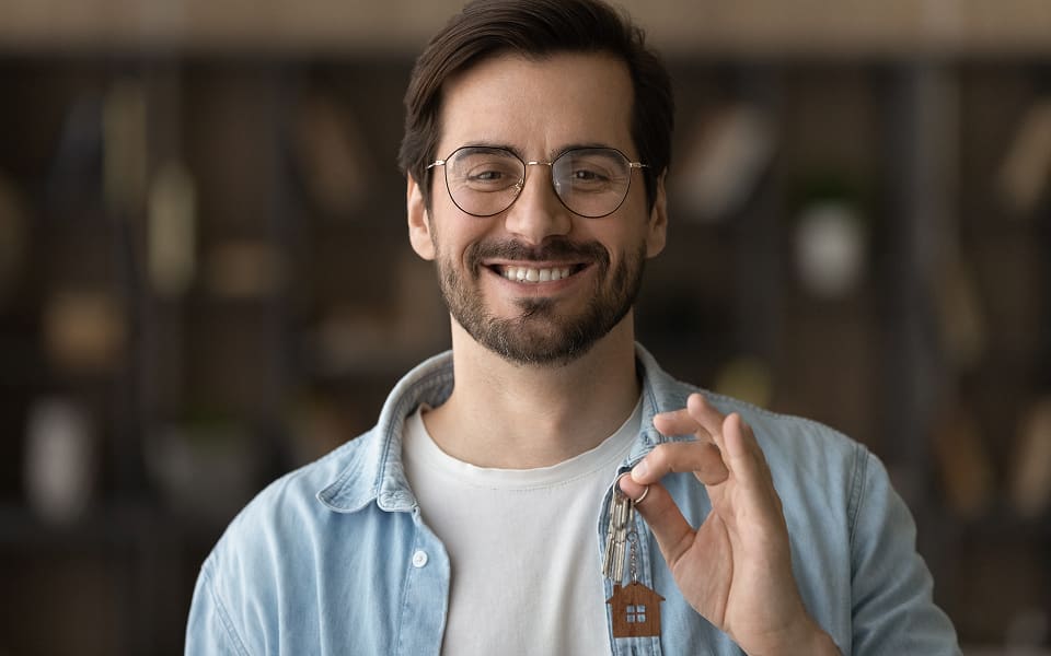 A smiling new hire holding the keys to his new home